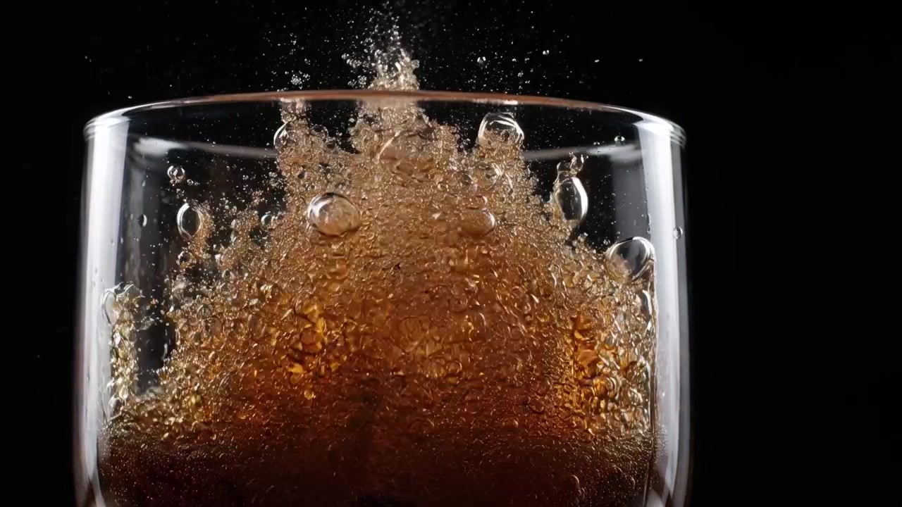 Bevanda Gassata che si Versa su un Cubetto di Ghiaccio in un Bicchiere