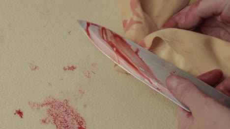 mano ensangrentada del asesino criminal que limpia la sangre de un cuchillo después de apuñalar
