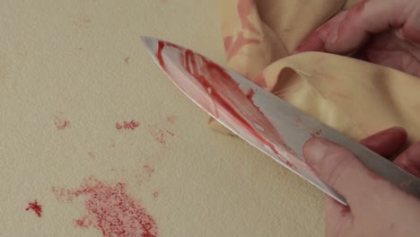 bloody hand of criminal murderer wiping blood of a knife after stabbing