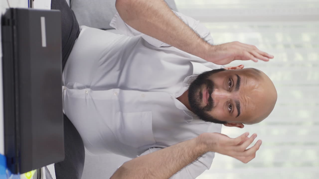Vertical video of Home office worker man has fatigue.