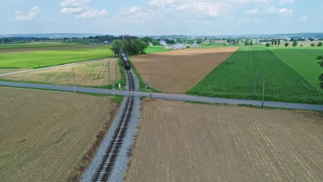 An-Aerial-View-of-an-Approaching-Steam-Passenger-Train,-Blowing-Smoke-and-Steam-on-a-Partially-Sunny-Day