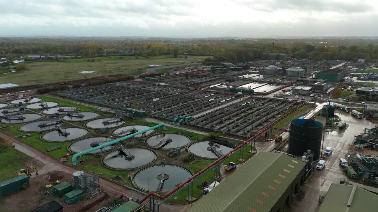 Overhead aerial drone footage of Severn Trent wastewater facility with circular tanks, sedimentation pools, silos and large scale layout Leicester