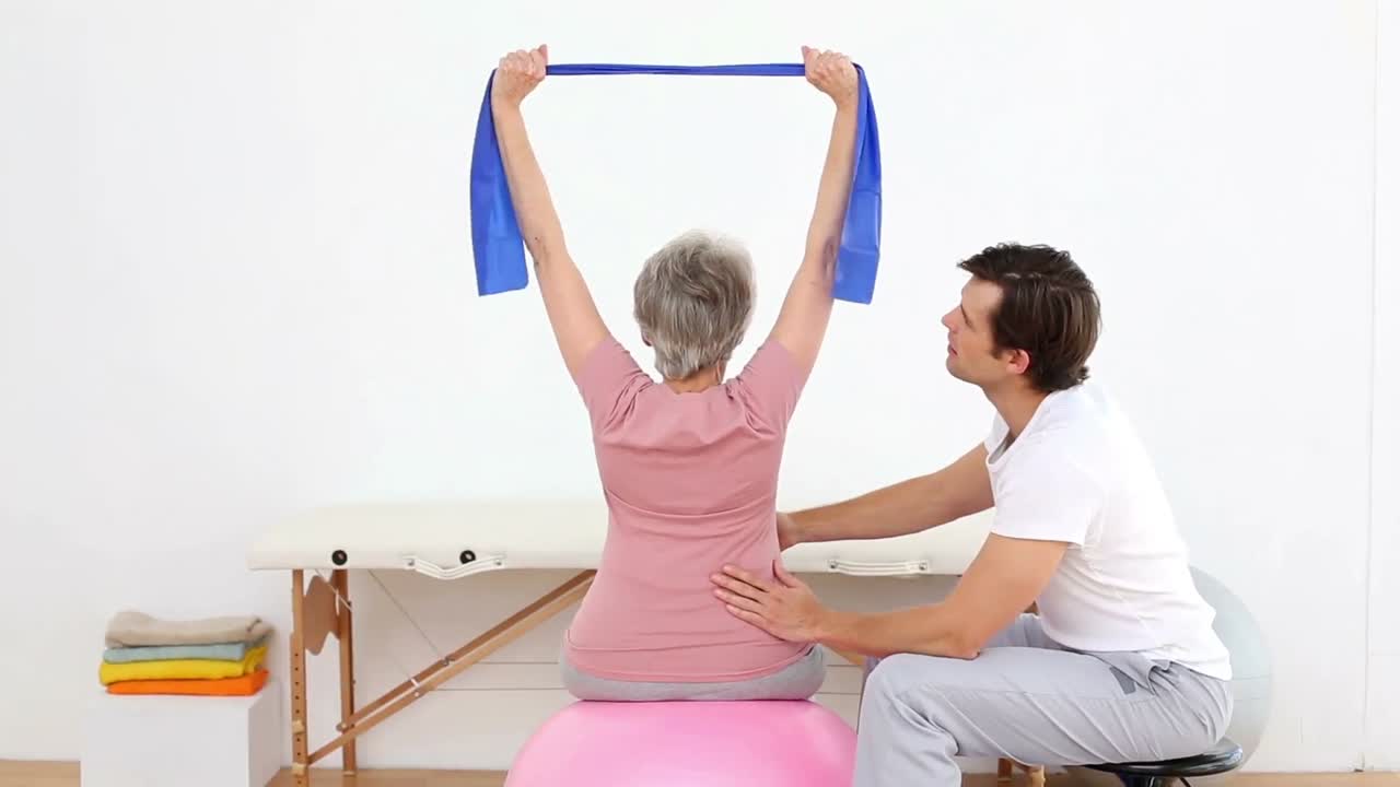fisioterapeuta observando al paciente estirar la banda de resistencia