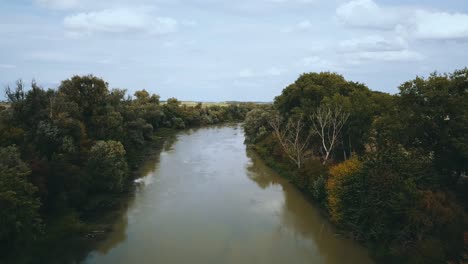 Toma-De-Drones-De-Un-Río-Lento-Y-Fangoso-Entre-Campos-Y-árboles.