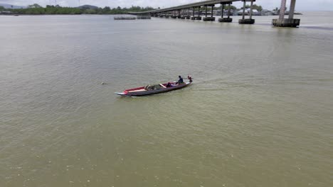 bote pequeño con pescadores flotando alrededor de la isla en tailandia con vista a la montaña