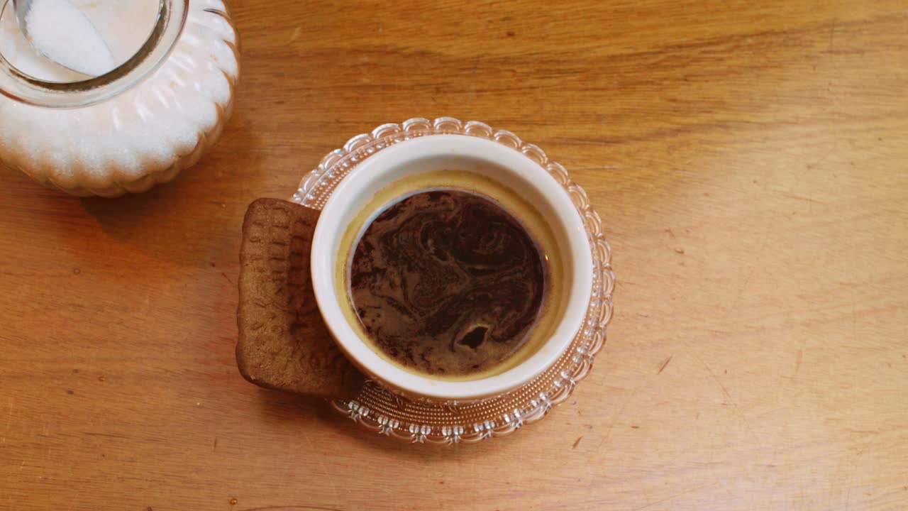 Adding two spoonfuls of sugar to coffee cup and stirring, Overhead Close Up