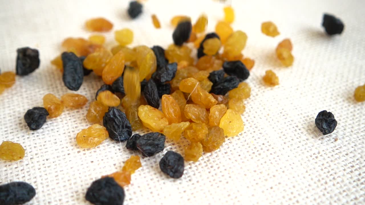 Raisins secs clairs et foncés. Filmés en tombant sur un sac. Ralenti