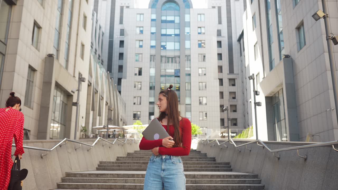 Giovane donna con laptop sulle scale della città