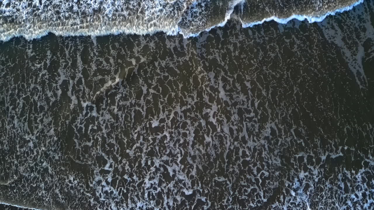 Aerial drone view of waves crashing on the beach in The Hague, Netherlands