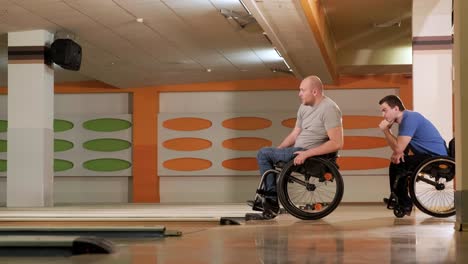 two young disabled men in wheelchairs playing bowling in the club