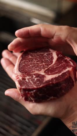 raw ribeye steak in hands