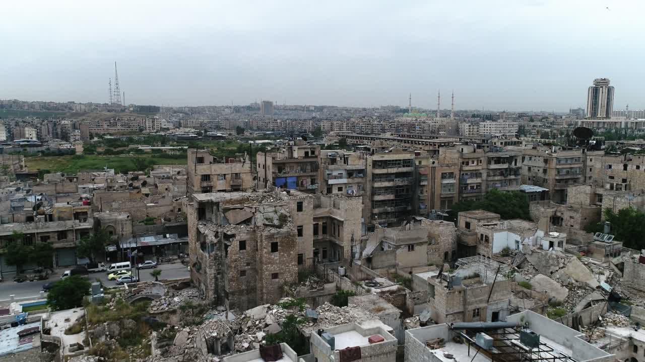 A syrian city from above with cars driving on a road. Some of the buildings are still in ruins after the civil war 10 years ago - aerial view with a drone 4K