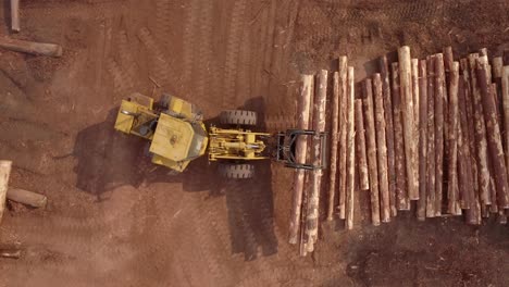 4k-Antena-Arriba-Hacia-Abajo-De-Un-Vehículo-Cargador-Frontal-De-Madera-Amarilla-Con-Garras-Moviendo-Troncos