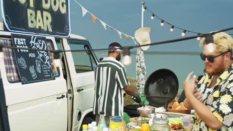 middle eastern man cooking hot dogs for customers at food truck