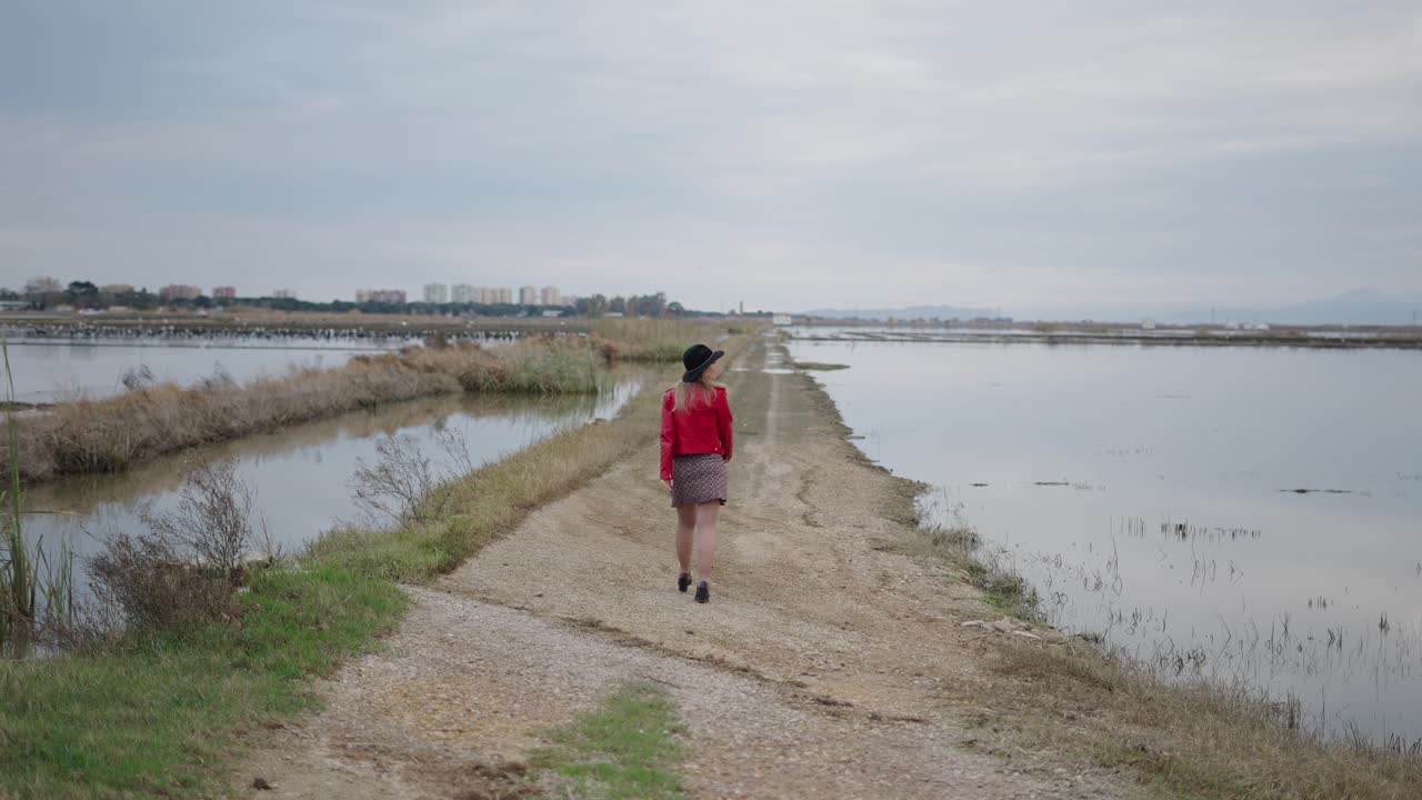 Woman Walking Along a Path Through a Marsh