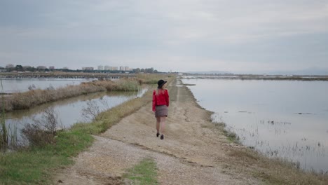 woman walking along a path through a marsh