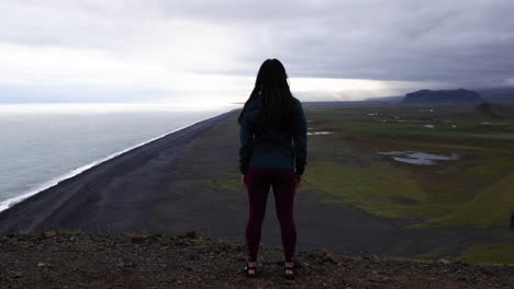 Young-woman-stands-overlooking-the-coastal-cliffs-near