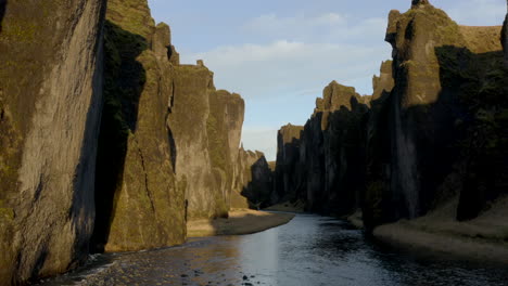 low aerial shot though fjaðrárgljúfur canyon looking up at the moss covered walls