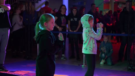 slow motion shot of two little girls trying to repeat dancing moves from the screen. dance party.