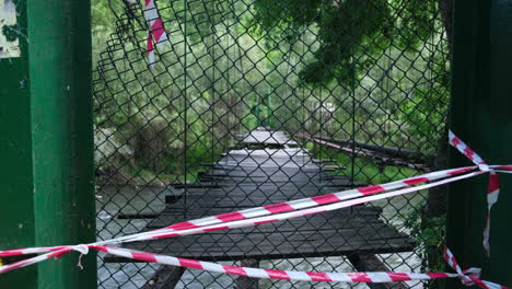 viejo puente de madera cerrado con barras faltantes sobre un río en el bosque