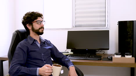 apuesto hombre latino bebiendo té haciendo una pausa en el trabajo en la oficina