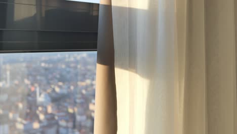 vista de la ciudad a través de una ventana con cortinas transparentes