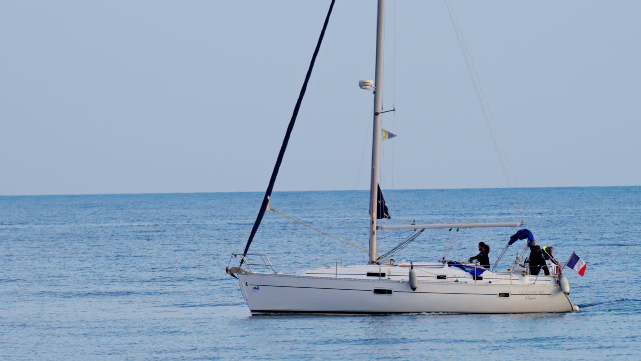 Antibes, France - February 14, 2025: Boat with the flag of France moving on the sea on a cloudy day
