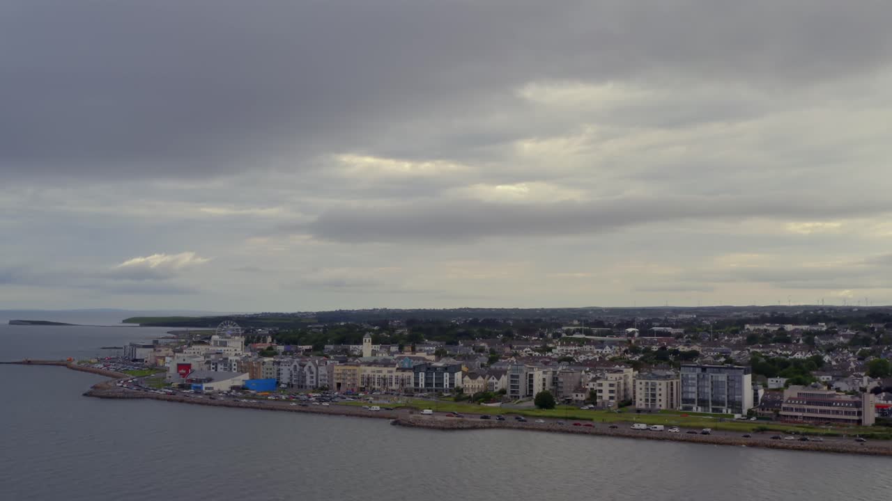 Carrellata aerea che si avvicina al villaggio di Salthill dalla baia di Galway sotto un cielo nuvoloso e spettacolare