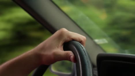 close-up shot of a hand tightly gripping the steering wheel of a car while driving