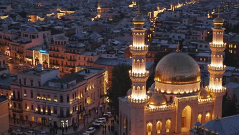 las luces doradas adornan una majestuosa mezquita, sus minaretes se extienden hacia el cielo del crepúsculo, mientras que el paisaje urbano circundante está lleno de actividad durante el mes sagrado de ramadán.
