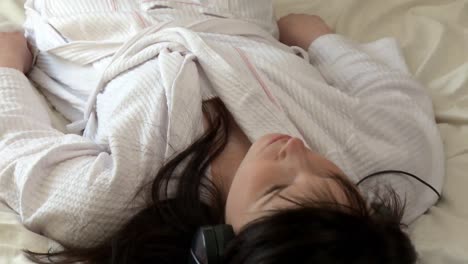 침대에 누워 음악을 듣는 조용한 여자