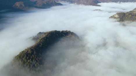 aerial view of valley amidst huge mountains, all covered with thick blanket of dense clouds