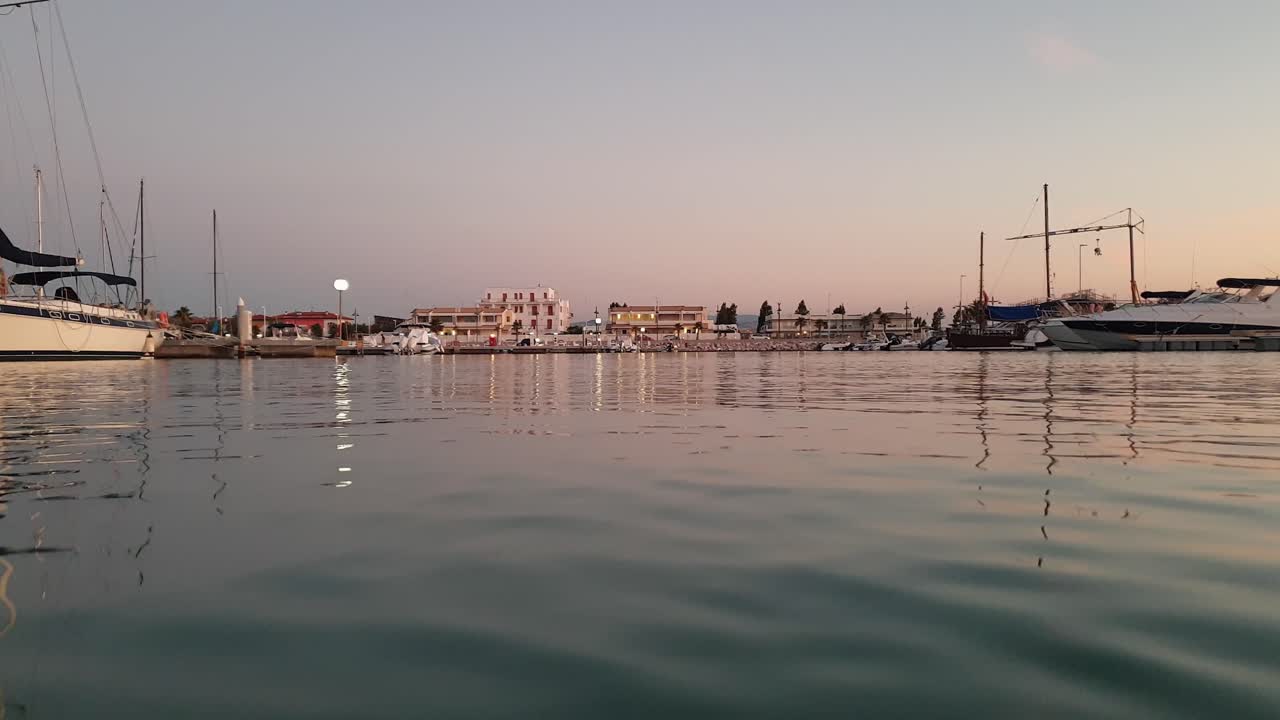 perspectiva personal de la superficie del agua en ángulo bajo del barco que regresa al puerto al atardecer