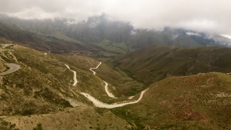 Aerial---A-winding-road-in-Northern-Argentina-below-heavy-clouds,-wide-shot