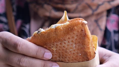 una mujer sosteniendo un sándwich y comiéndolo.
