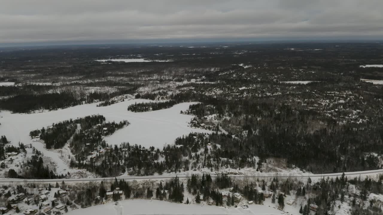 Ice roads scattered throughout the frozen lake hidden among the boreal forest in northern Canada
