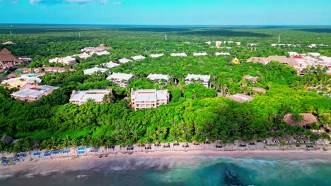 Beach-view-of-a-resort-in-Tulum-Mexico-with-beach-chairs-and-umbrellas-and-large-waves-breaking-on-the-shore