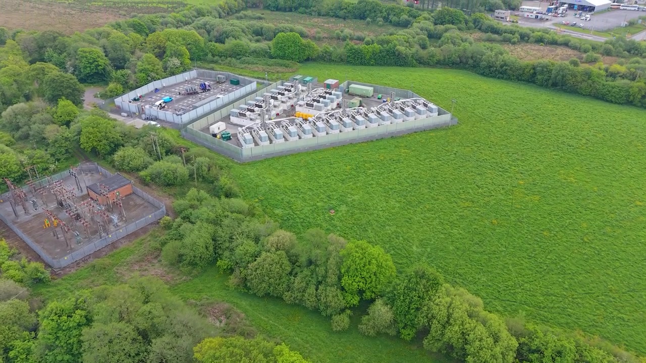 Aerial Reveal of Modern Gas Peaking Plant with exhaust stacks, generators, cooling systems. Facility provides rapid-response electricity to the grid during peak demand. Energy infrastructure. UK.