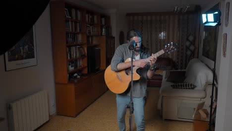 man singing and playing guitar at home