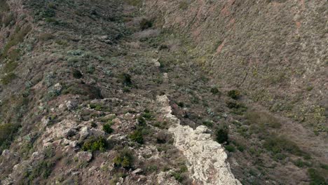 fpv tiro inclinado hacia abajo de la pared rocosa en la montaña en tenerife, españa