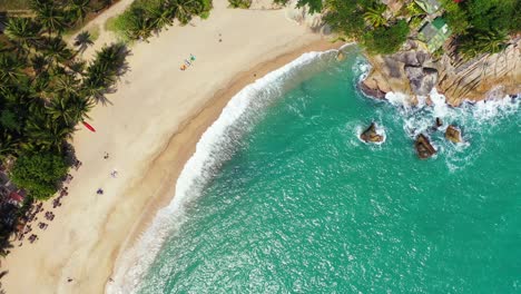 paradise exotic beach with white sand and beautiful cliffs splashed by turquoise sea waves in tropical island with palm trees forest in thailand