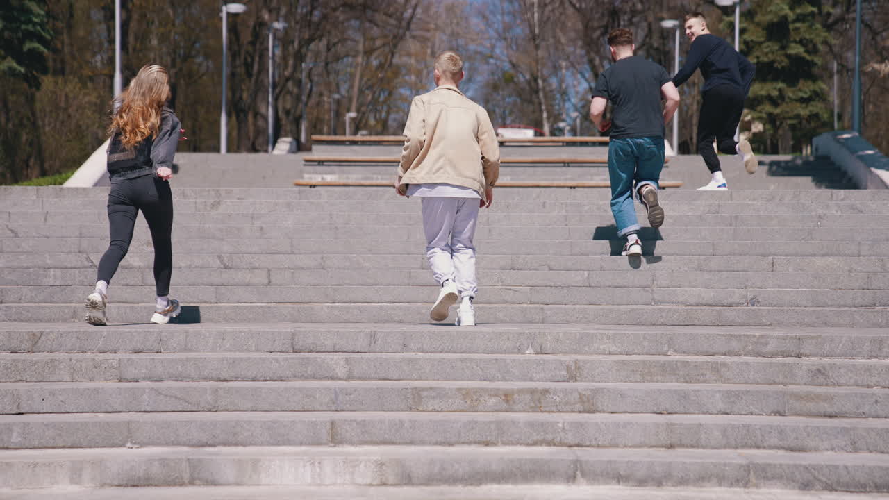 Happy friends running into the park at the stairs. Good looking guys spending time with friends in park in a sunny day. Young people enjoying the time together concept