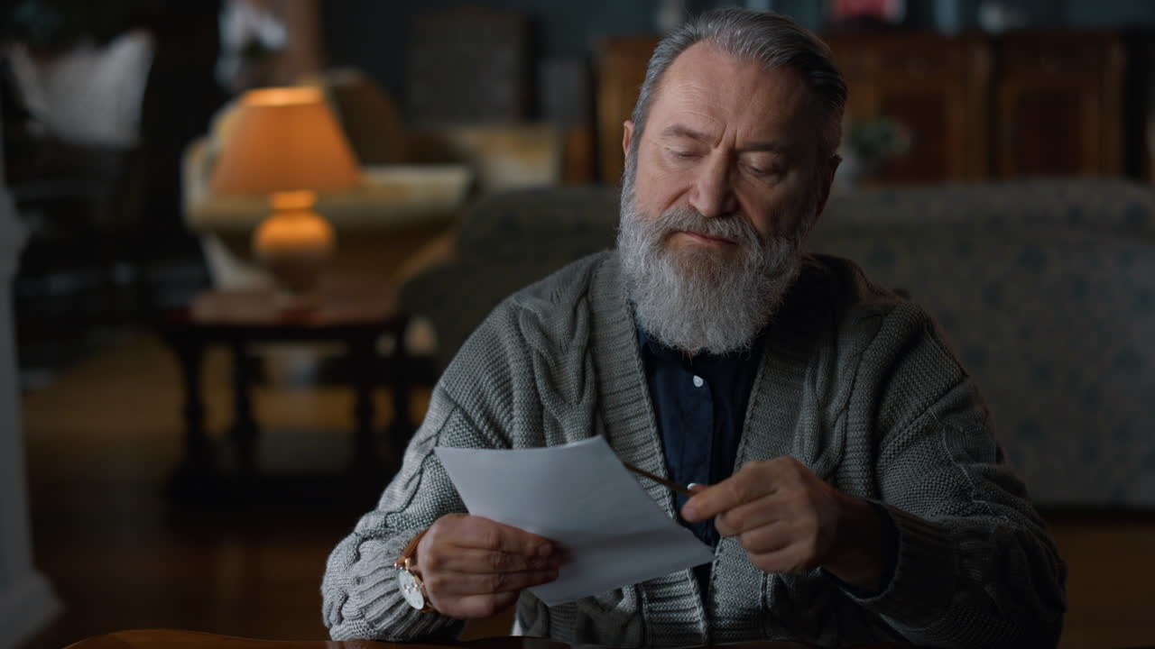 старший мужчина разрезает конверт ножом в классическом шкафу.