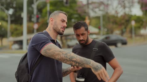 two men use a smartphone for navigation and discuss directions on a city street