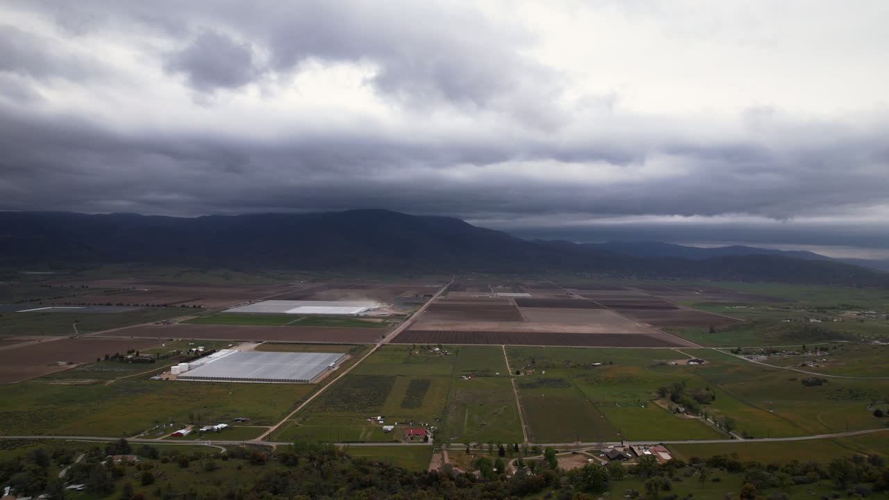 커다란 농장 들, 온실 들, 그리고 산 들 이 배경 으로 있는 구름 이 많은 날 에 캘리포니아 주 테하차피 의 공중 사진