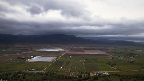 vista aérea de tehachapi, california en un día nublado con grandes campos de cultivo, invernaderos y montañas en el fondo