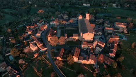 aerial shot of a french village with a church at sunrise