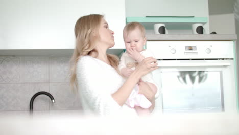 Mamá-Con-Bebé-Yendo-A-La-Cocina-Blanca.-Mujer-De-Belleza-Con-Un-Niño-Pequeño-En-La-Mano