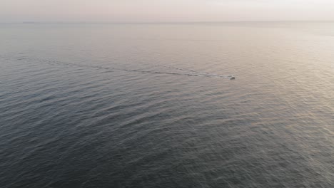 A-boat-motors-along-a-calm-sea-during-a-winter-sunrise-off-the-coast-of-Maine-AERIAL