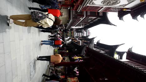 people walking through a traditional chinese street lined with ornate buildings